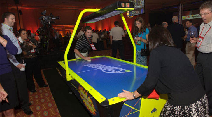 Image: Corporate employees enjoying air hockey with co-workers. Recreational activity planning and corporate team builidng activiites organized by Benchmarc360.